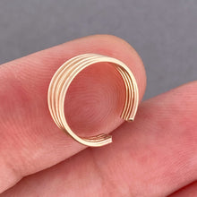 Load image into Gallery viewer, A gold ear cuff held between two fingers against a grey background.