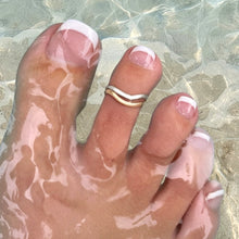 Load image into Gallery viewer, A close-up of a foot in shallow water wearing a double-band wavy ring with one gold band and one silver band, styled with a French manicure.